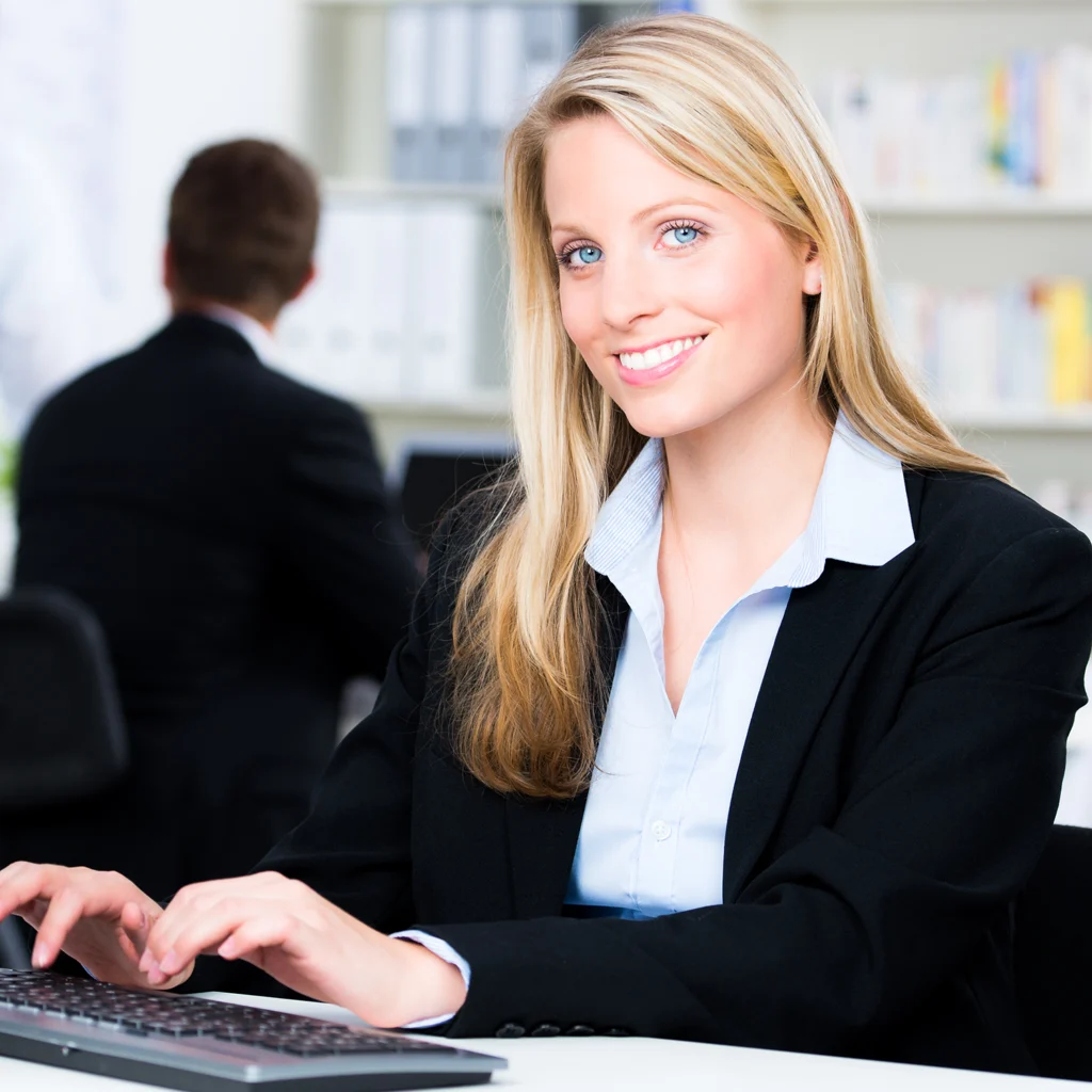 Frau arbeitet am Computer und lächelt – Symbolbild für Erfolg in der Steuerberaterprüfung