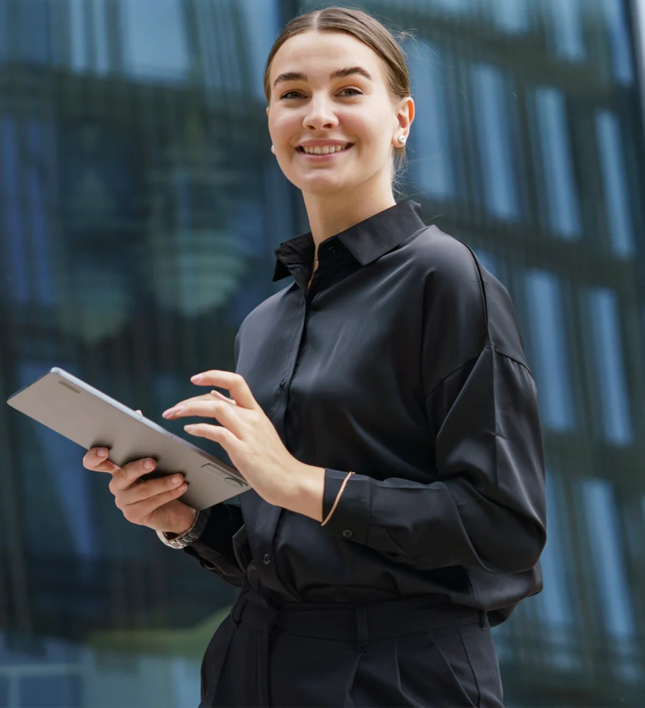 Geschäftlich gekleidete Person nutzt digitale Anwendungen vor einem modernen Bürogebäude in urbaner Umgebung.
